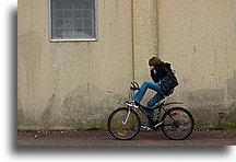 Rowerzystka::Dziewczyna na rowerze przy ścianie magazynu z czasów ery prohibicji::